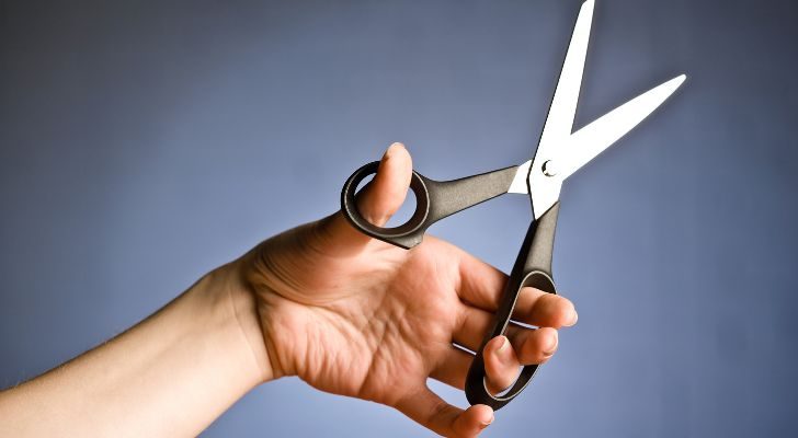 A left-handed person holding a pair of scissors