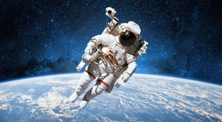 An astronaut in a space suit floating in space above the Earth