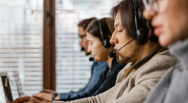 Several men and women wearing headsets working in a call center