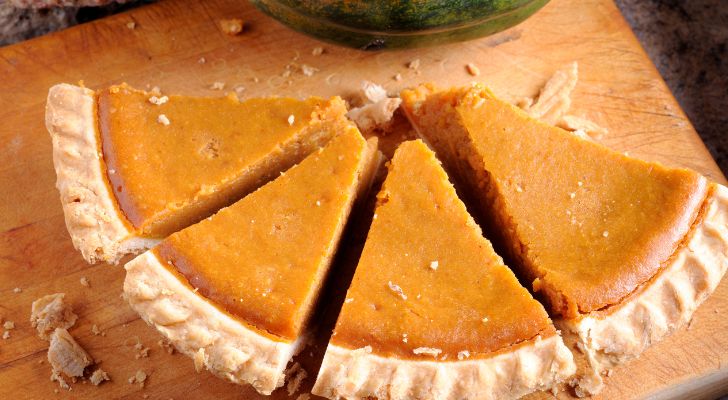 Slices of crumbling pumpkin pie sitting on a chopping board