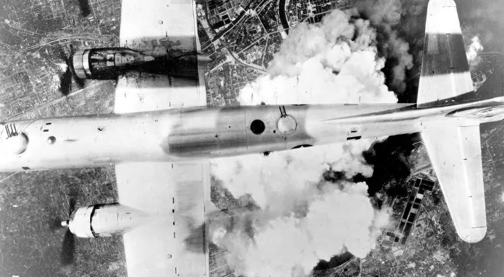 A B-29 bomber flying over a large cloud of smoke in Japan