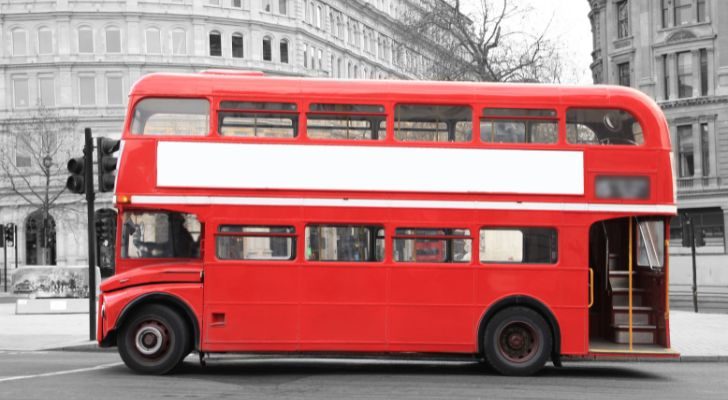 A classic red double-decker bus driving through Charing Cross in London