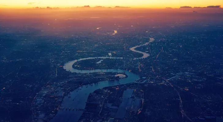 The Thames river winding through London under a sunset