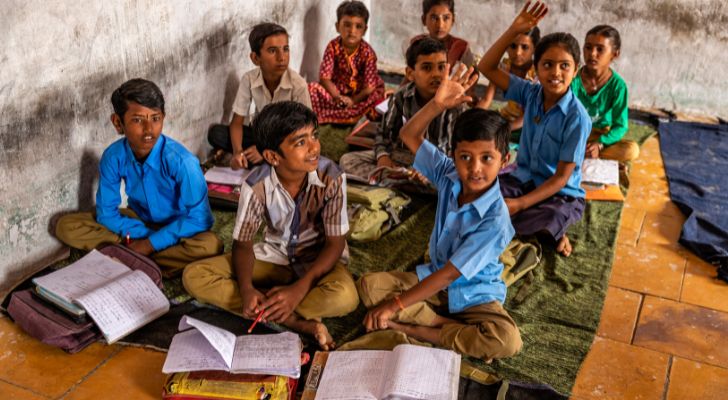 A group of Indian school children learning from books while in a class