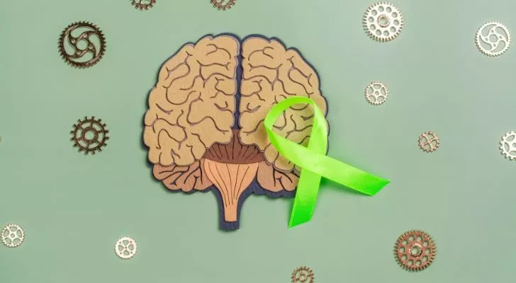 A green ribbon laid on top of a picture of a brain