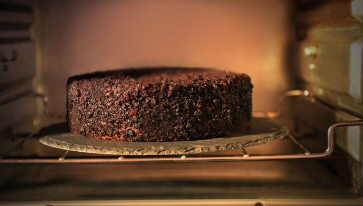 A blackened cake on a tray inside an oven, resembling possible superstition involving burnt food.