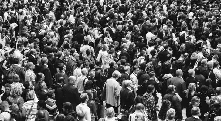 A large crowd of people gathering and looking in one direction