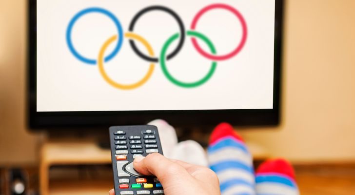 A person sits in front of a TV showing the Olympic rings