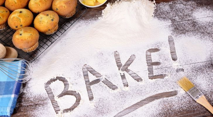 The word "bake" is written in flour next to an assortment of baked goods