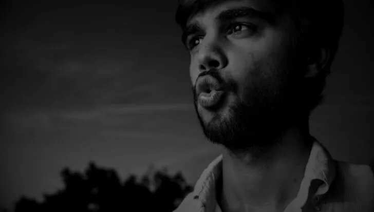 Black and white photo of a person with a beard whistling