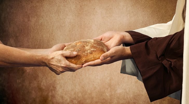 One person ceremoniously handing a loaf of bread to another