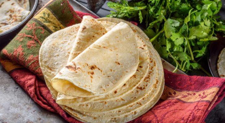 A stack of tortillas is placed on some fabric