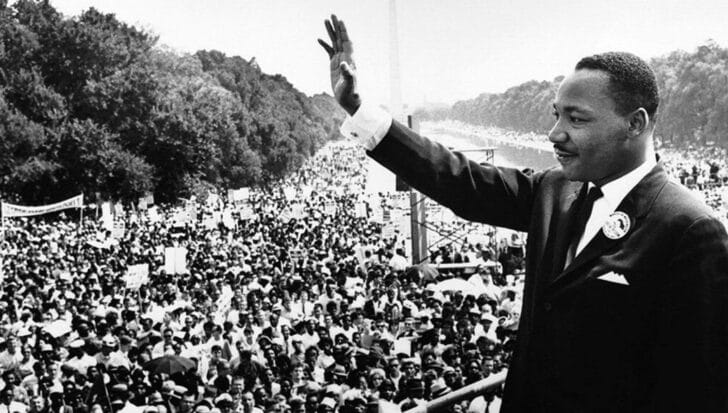 Dr. Martin Luther King Jr. waving to a large crowd during a civil rights event