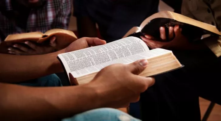 A group of people sitting together with open Bibles