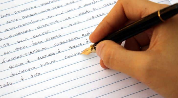 A person writing notes on lined paper using a fountain pen