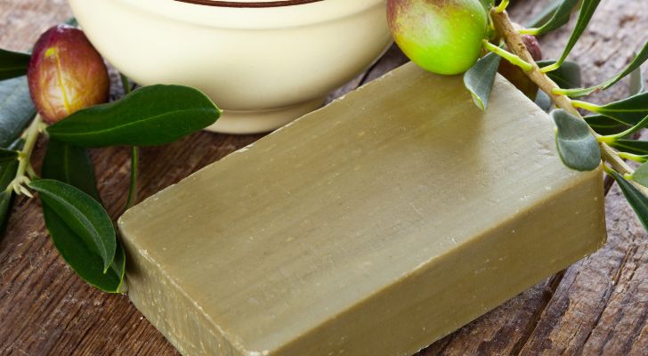 A bar of soap made from olive oil placed next some olive branches