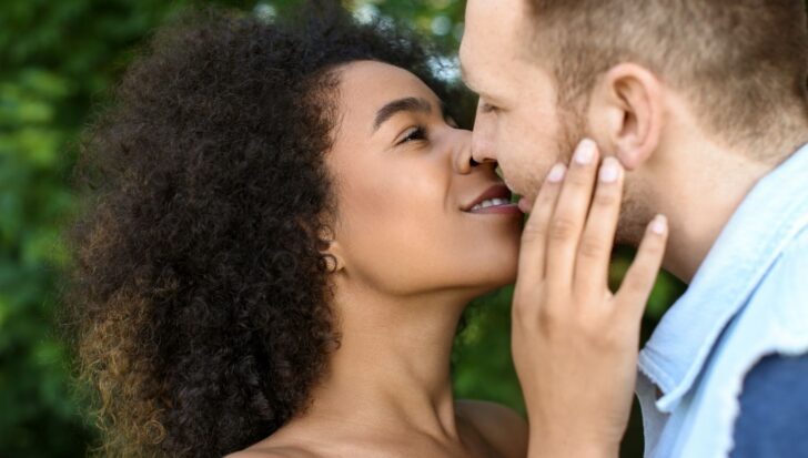 A couple closely facing each other, appearing to share a kiss