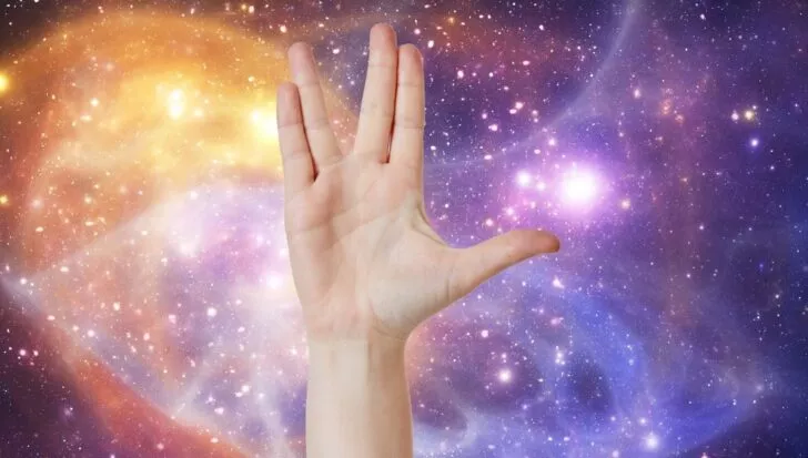 Hand forming the Vulcan salute against a colorful galaxy background