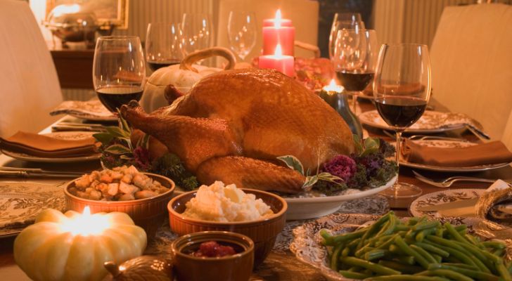 A thanksgiving dinner laid out on a table with candles and side dishes