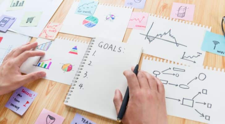 A person making a list of goals with charts, graphs and notes surrounding it