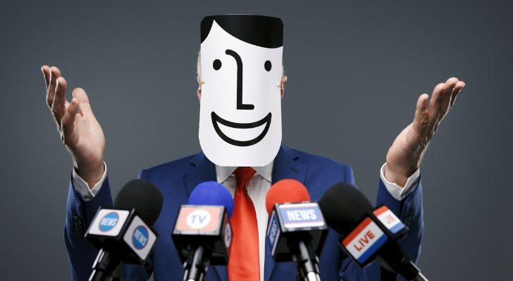 A man at a press conference with a 'generic person' mask on his face