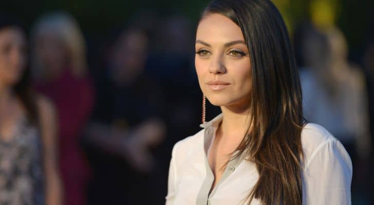 Mila Kunis in a white shirt standing in front of a crowd