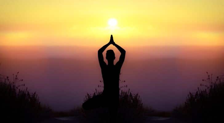 The silhouette of a person performing yoga at sunrise