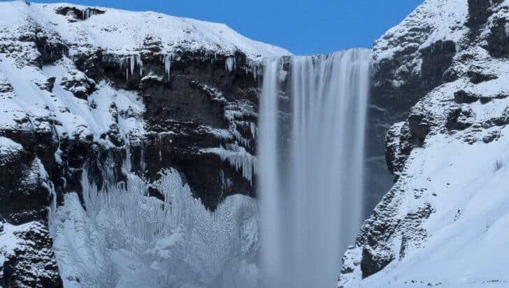 A snowy waterfall surrounded by icy cliffs, illustrating extreme cold conditions