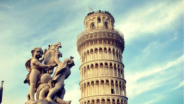 The Leaning Tower of Pisa with a foreground statue of cherubs holding a shield