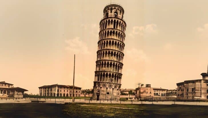 The Leaning Tower of Pisa standing prominently with surrounding buildings against a clear sky