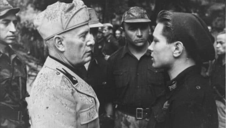 Group of Italian leaders, including Benito Mussolini, in uniform engaged in conversation