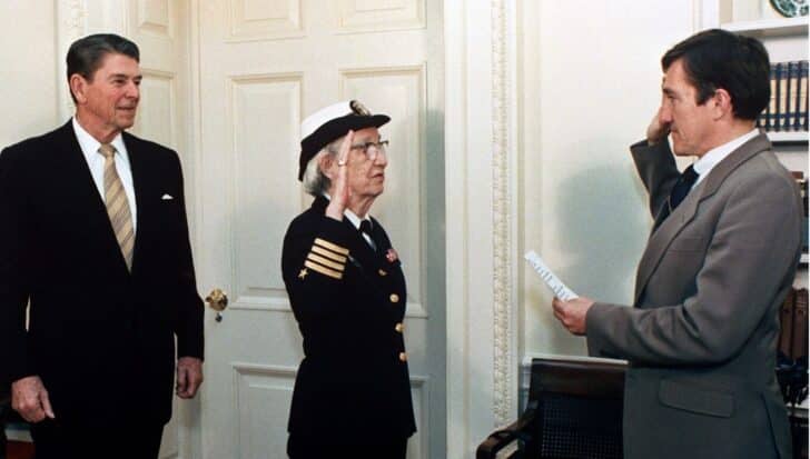 Grace Hopper in a military uniform saluting during a ceremony with the president