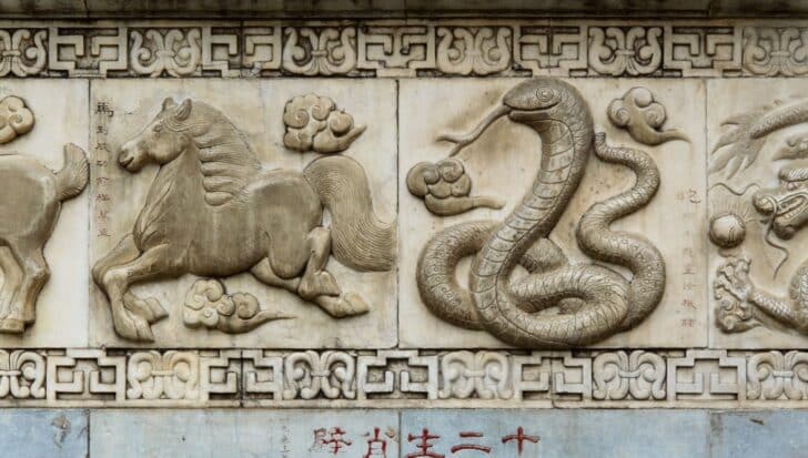 Stone carving depicting a snake in a coil with clouds, symbolizing the Year of the Snake