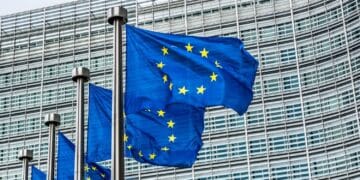 European Union flags waving in front of a modern glass building