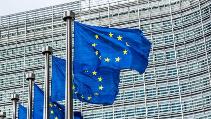 European Union flags waving in front of a modern glass building