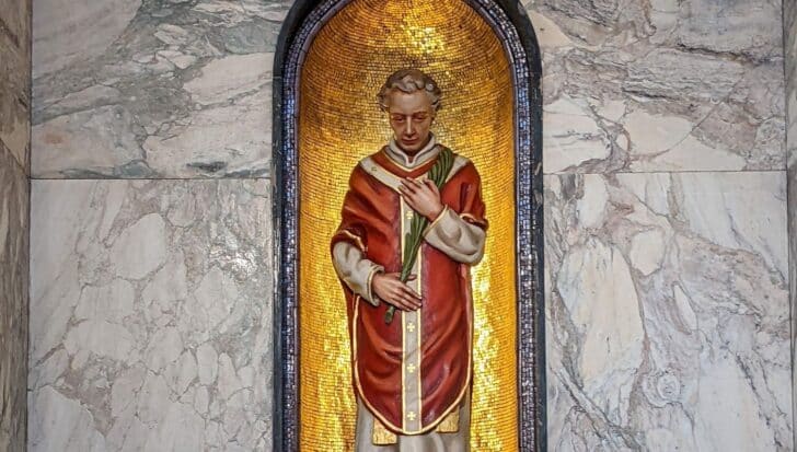 Statue of Saint Valentine in a niche with a golden background, depicted in a red robe holding a palm leaf